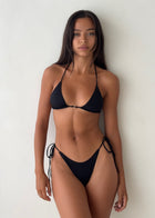 Woman wearing a black bikini against a white background