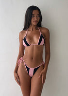 Woman wearing a pink and black bikini against a plain background